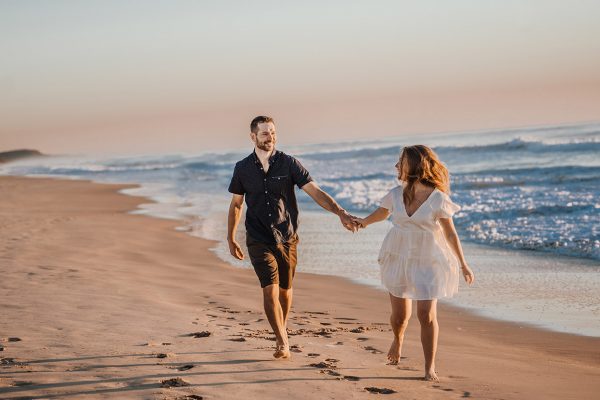 Engagement Photography couple holding hands on beach at sunset