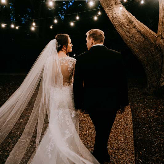 Wedding Photography bride and groom walking under fairy lights square